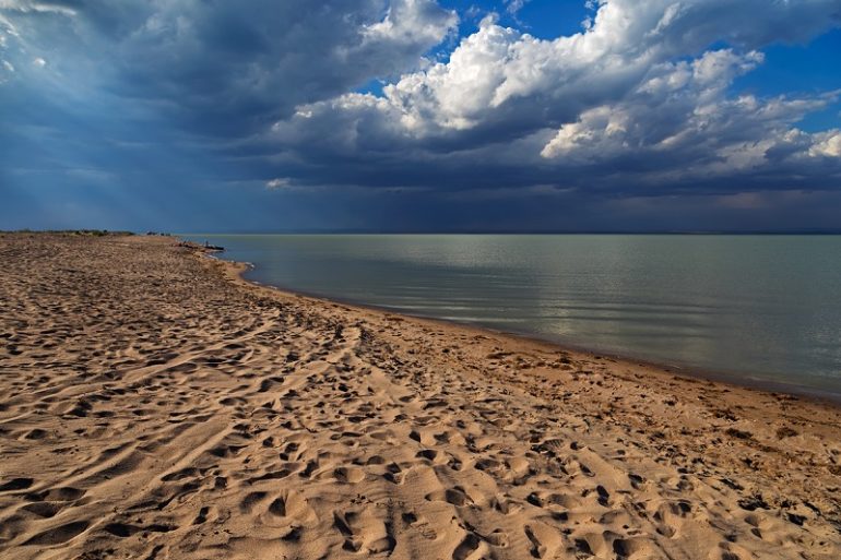 Песчаный пляж Капчагайского водохранилища под грозовым небом