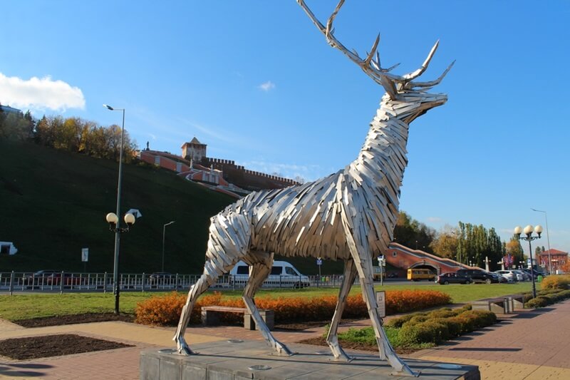 Металлический олень — современный символ Нижнего Новгорода у Чкаловской лестницы Скульптура «Олень» на набережной Нижнего Новгорода на фоне Чкаловской лестницы и кремля